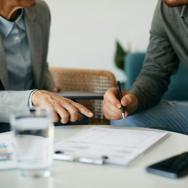 Going through the options of preparing your home Two people discussing documents with a glass of water and a phone on the table.
